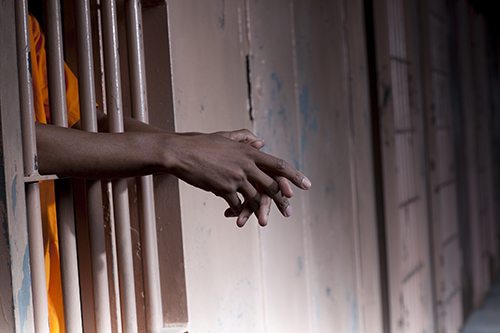 Prisoner's Arms Resting On Cell Bars